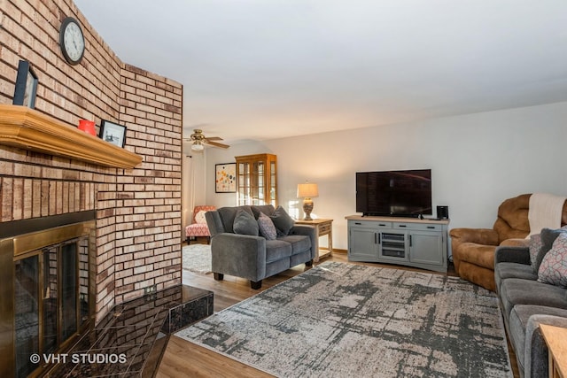 living room with a fireplace, a ceiling fan, and wood finished floors