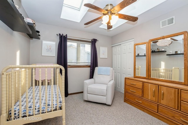 bedroom featuring a skylight, a closet, light colored carpet, visible vents, and baseboards