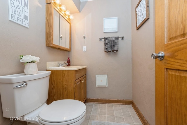 half bath with toilet, baseboards, and vanity