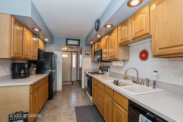 kitchen with tasteful backsplash, light countertops, a sink, and black appliances