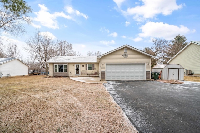 ranch-style home featuring cooling unit, a garage, and a shed