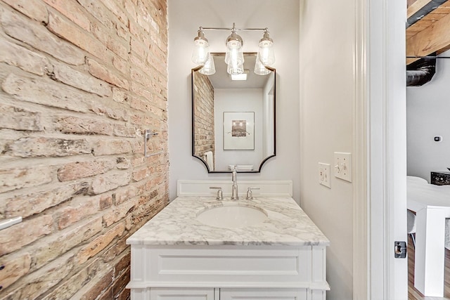 bathroom featuring brick wall and vanity