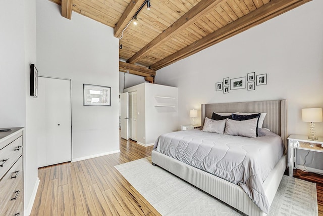 bedroom with beamed ceiling, track lighting, wood ceiling, and light hardwood / wood-style floors