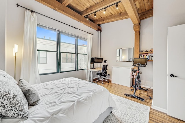 bedroom featuring beamed ceiling, track lighting, wooden ceiling, and light hardwood / wood-style floors