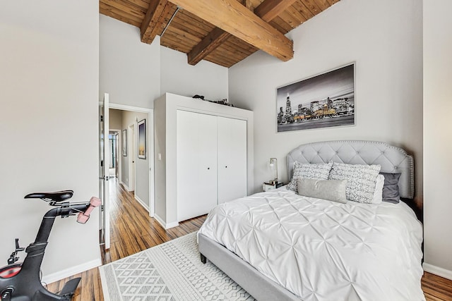 bedroom with wood ceiling, hardwood / wood-style floors, a closet, and lofted ceiling with beams