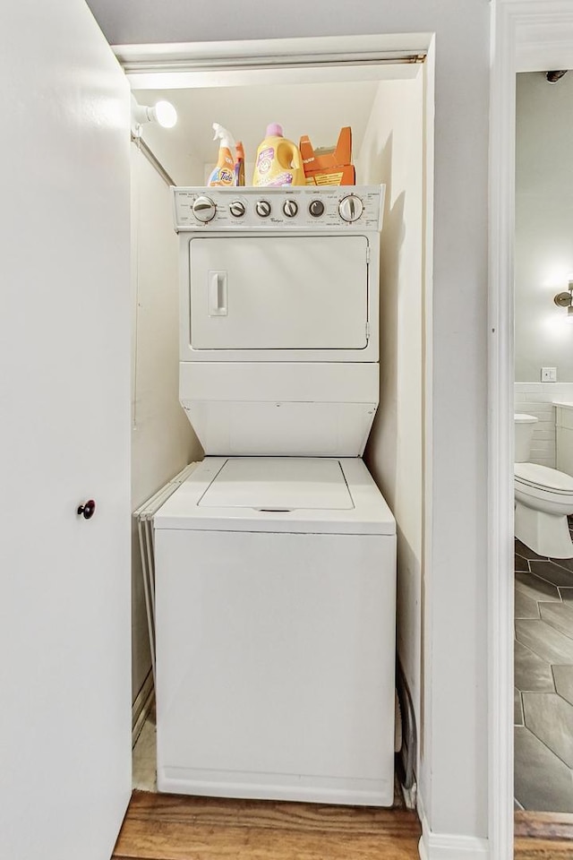 washroom with stacked washing maching and dryer and light hardwood / wood-style floors