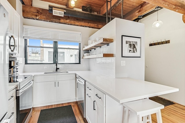 kitchen featuring appliances with stainless steel finishes, sink, white cabinets, hanging light fixtures, and beam ceiling