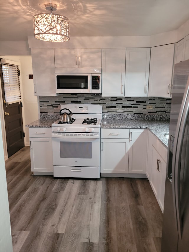 kitchen with hardwood / wood-style floors, white cabinetry, decorative backsplash, light stone counters, and white appliances