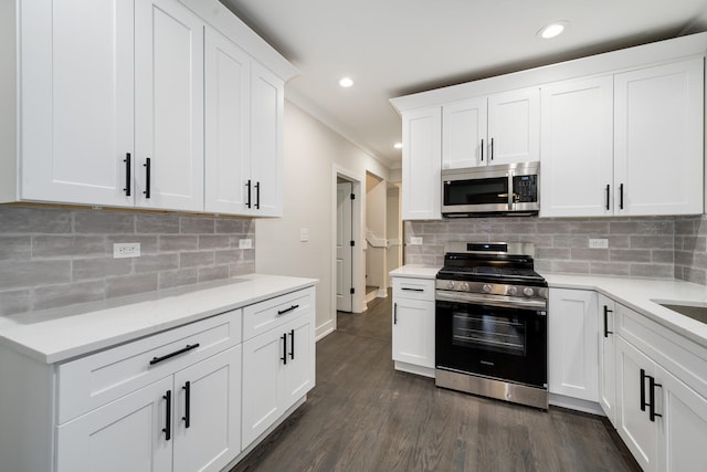 kitchen with dark hardwood / wood-style flooring, tasteful backsplash, white cabinets, and appliances with stainless steel finishes