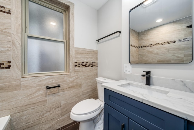 bathroom featuring vanity, tile walls, and toilet