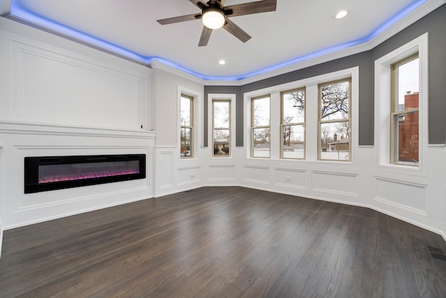 unfurnished living room with ceiling fan, ornamental molding, and dark hardwood / wood-style flooring