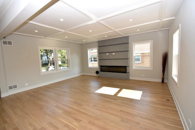 unfurnished living room with coffered ceiling, a fireplace, and light hardwood / wood-style floors