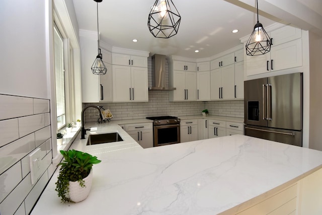 kitchen with pendant lighting, sink, appliances with stainless steel finishes, white cabinets, and wall chimney exhaust hood