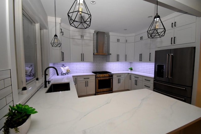 kitchen with pendant lighting, wall chimney range hood, sink, and appliances with stainless steel finishes