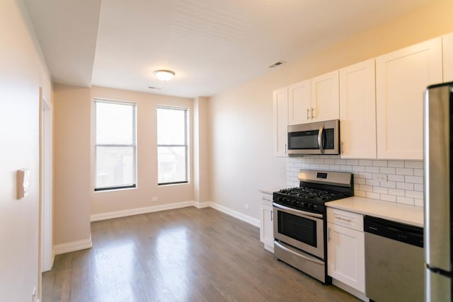 kitchen with dark wood finished floors, stainless steel appliances, light countertops, backsplash, and white cabinets