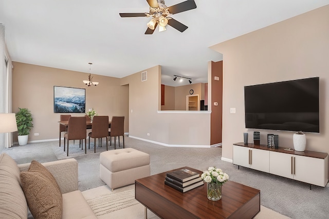 carpeted living room with rail lighting and ceiling fan with notable chandelier