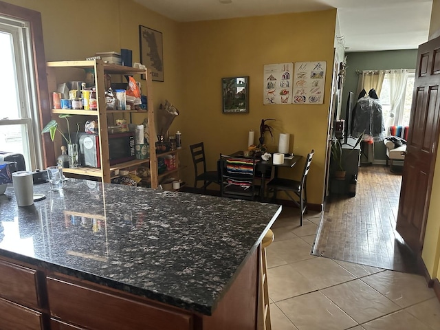 interior space featuring light tile patterned floors and dark stone counters