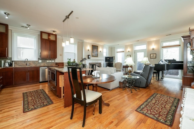 dining space with ornamental molding, a healthy amount of sunlight, and light wood-style flooring