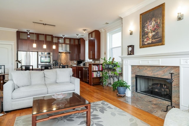 living room with light wood finished floors, ornamental molding, and a fireplace