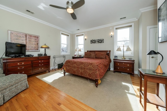 bedroom with a ceiling fan, crown molding, visible vents, and wood finished floors