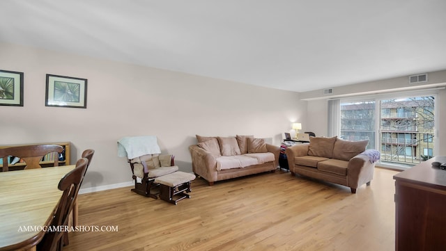 living room featuring light wood-style floors, baseboards, and visible vents