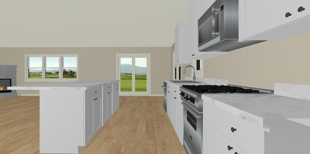 kitchen featuring white cabinets, sink, stainless steel stove, and light wood-type flooring