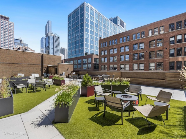 view of community with a fire pit, a yard, and a city view