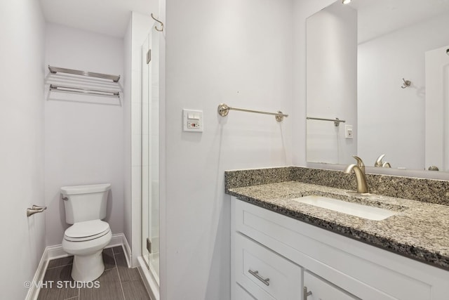 bathroom with vanity, toilet, and a shower with door