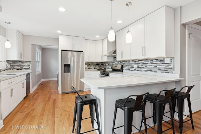 kitchen featuring sink, appliances with stainless steel finishes, white cabinetry, a kitchen breakfast bar, and kitchen peninsula