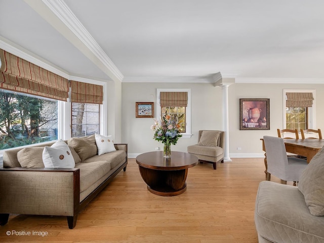 living area with ornamental molding, baseboards, light wood finished floors, and ornate columns