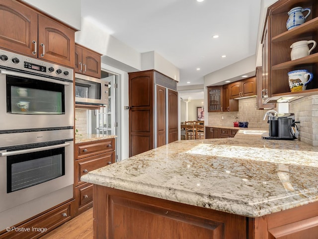 kitchen with light stone counters, a sink, appliances with stainless steel finishes, decorative backsplash, and open shelves