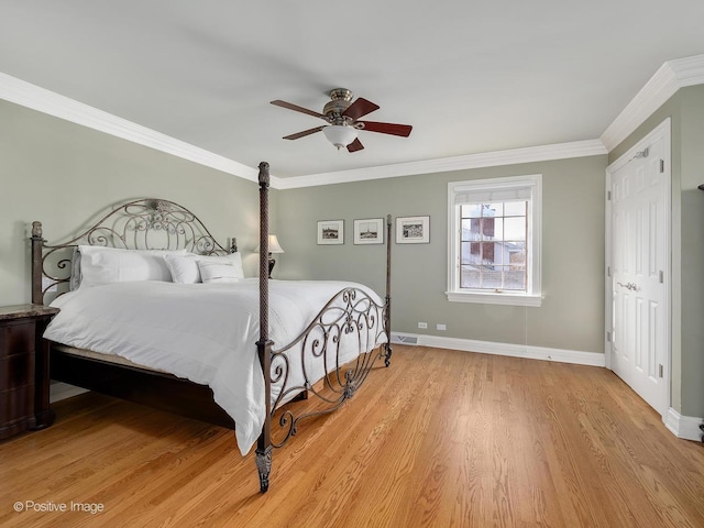 bedroom with light wood finished floors, visible vents, ornamental molding, ceiling fan, and baseboards