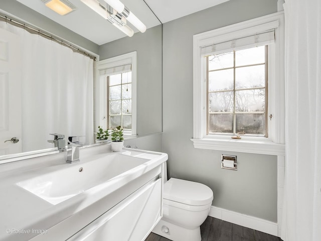 bathroom with visible vents, toilet, vanity, wood finished floors, and baseboards