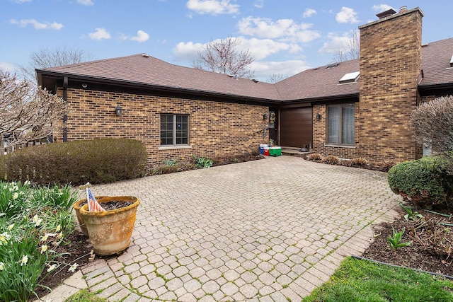 back of property featuring a patio area, brick siding, and a chimney