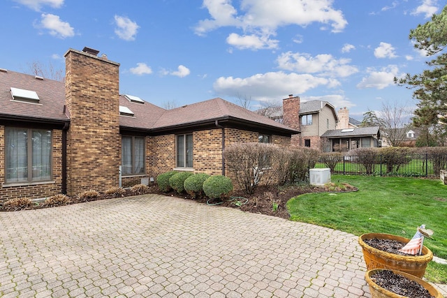 rear view of property featuring a patio area, brick siding, and a chimney