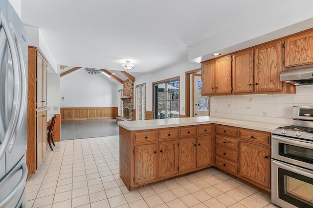 kitchen featuring range hood, stainless steel appliances, light tile patterned flooring, vaulted ceiling, and kitchen peninsula