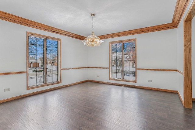 empty room with an inviting chandelier, wood finished floors, a wealth of natural light, and crown molding