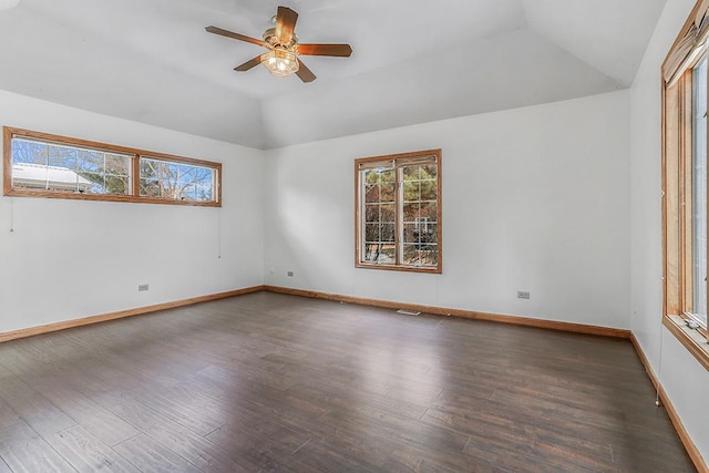 empty room featuring a healthy amount of sunlight, vaulted ceiling, baseboards, and wood finished floors