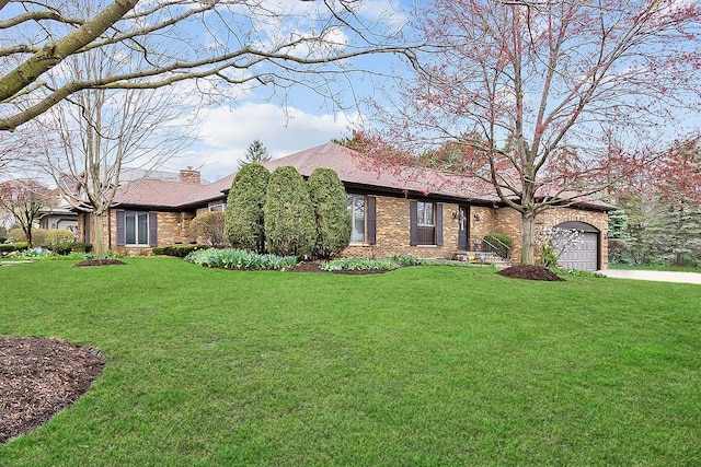 view of front of property with driveway, a chimney, an attached garage, a front lawn, and brick siding