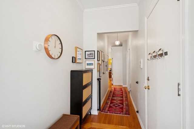 corridor featuring wood finished floors, baseboards, and ornamental molding