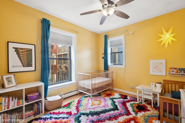 bedroom featuring wood finished floors, a ceiling fan, baseboards, and a baseboard radiator