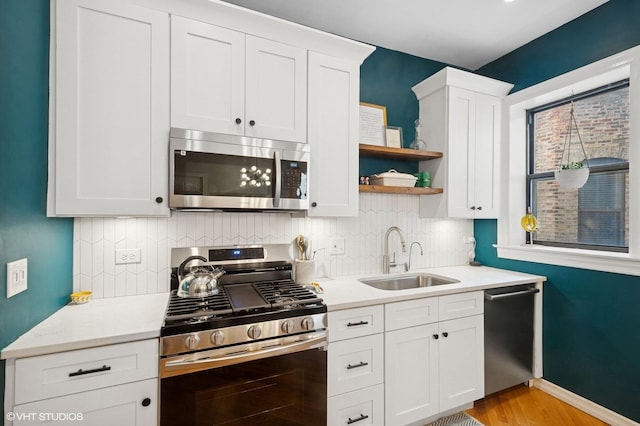 kitchen with a sink, tasteful backsplash, appliances with stainless steel finishes, and light countertops