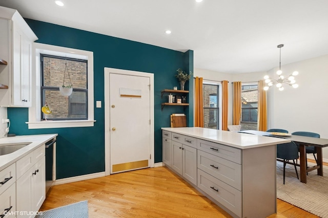 kitchen featuring light wood finished floors, a peninsula, light countertops, and open shelves