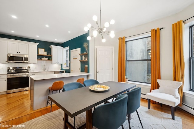 dining space with a chandelier, recessed lighting, a baseboard heating unit, and light wood-style floors