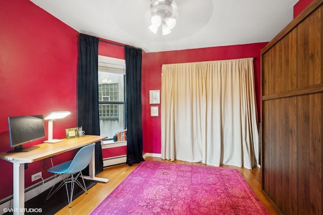 office space featuring ceiling fan, wood finished floors, and a baseboard radiator