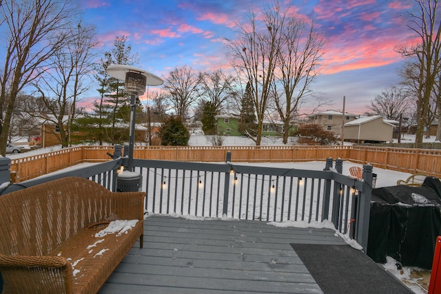 deck at dusk featuring a grill