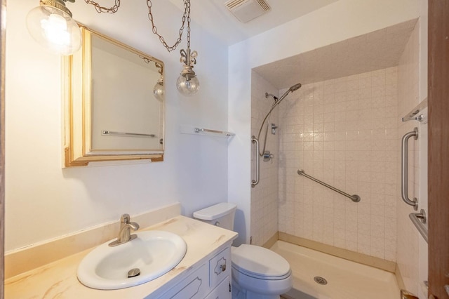 bathroom with vanity, tiled shower, and toilet