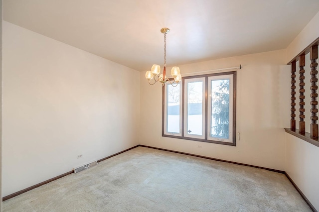 spare room with light colored carpet and a chandelier