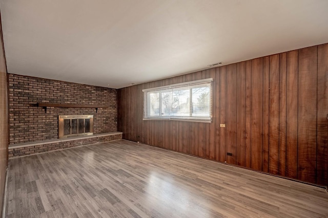 unfurnished living room featuring brick wall, a brick fireplace, and light hardwood / wood-style floors