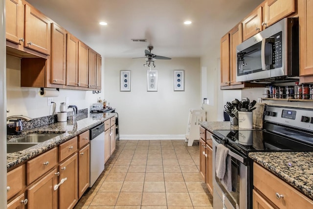 kitchen with sink, light tile patterned floors, dark stone counters, ceiling fan, and stainless steel appliances